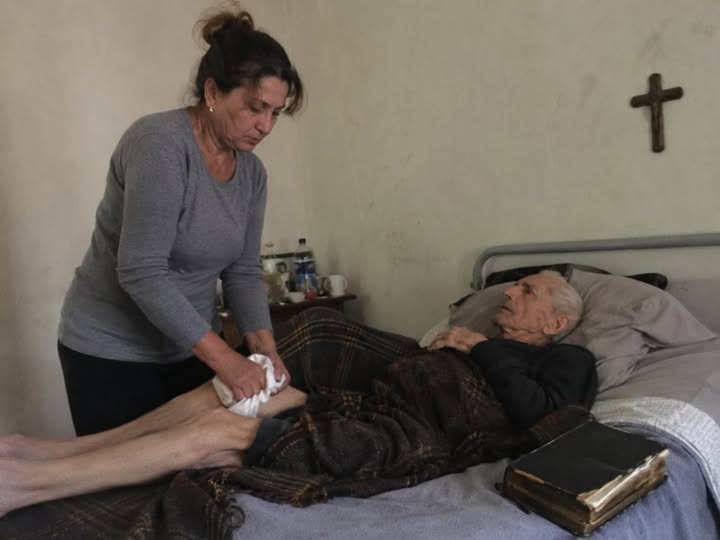 Zeven jaar lang waste, voedde en draaide ik mijn schoonvader in bed, altijd met een oude bijbel naast zijn kussen. En toen hij stierf, zei de notaris droogjes dat hij me niets had nagelaten. Pas een maand na de begrafenis vond ik een envelop onder zijn matras, wat de hele familie tot zwijgen bracht.